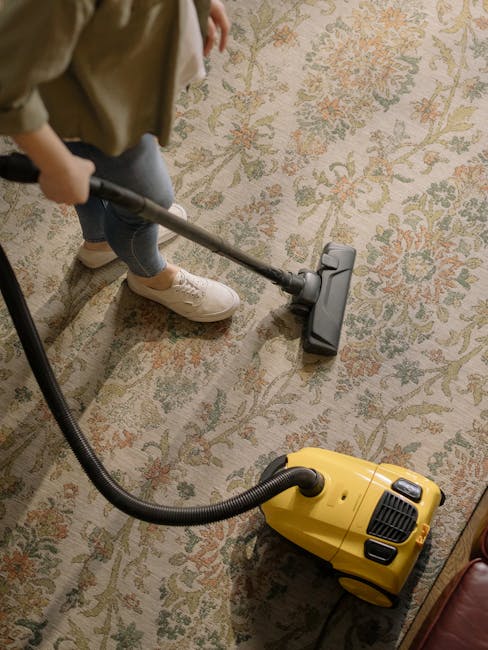 Close-up view of a beige carpet in a residential setting, showing a textured surface with visible fibers. The carpet appears clean and well-maintained, with a slight sheen indicating recent cleaning o